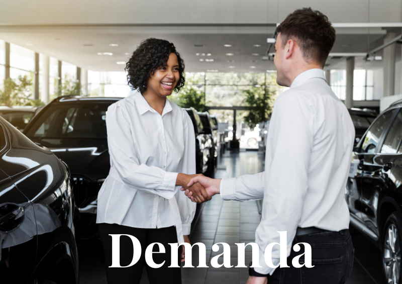 mulher negra apertando a mão de um homem branco, demanda escrita em branco, ambos estão em uma concessionária de carros
