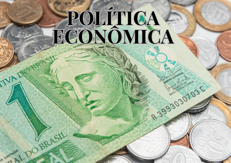 política econômica escrita em preto, nota de um real ao fundo e moedas de diversos valores