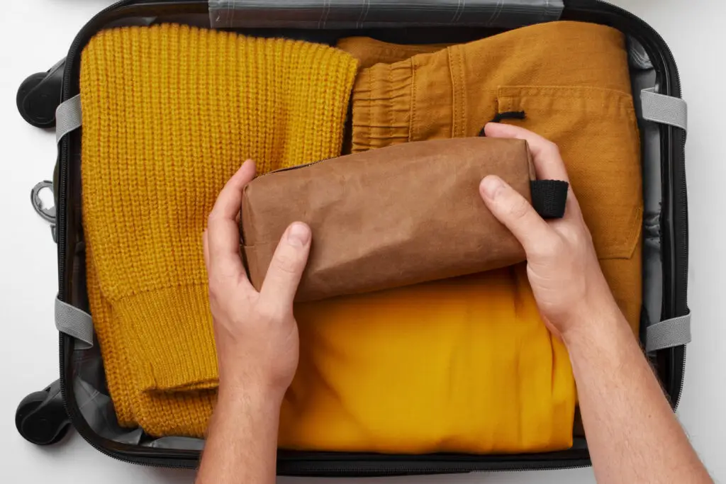 mãos brancas arrumando uma mala de viagem