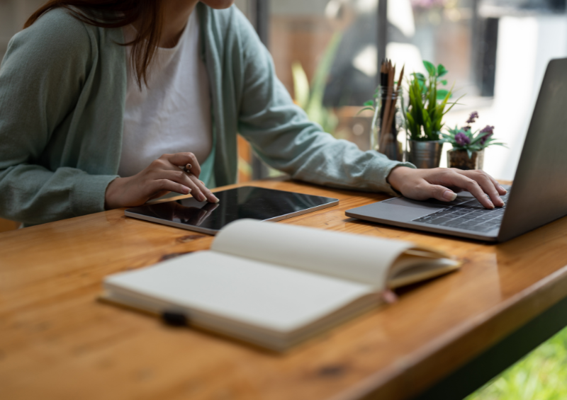 mulher no notebook e no tablet fazendo planos e um caderno aberto