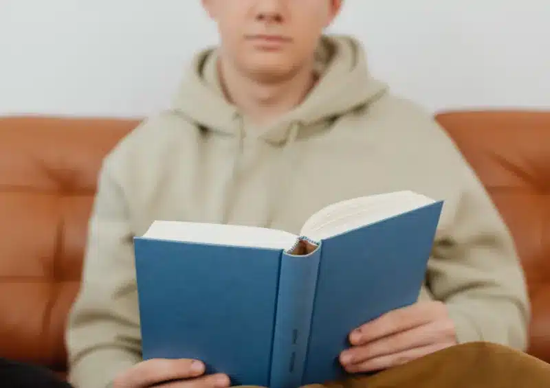 rapaz brranco lendo um livro de capa azul sem título