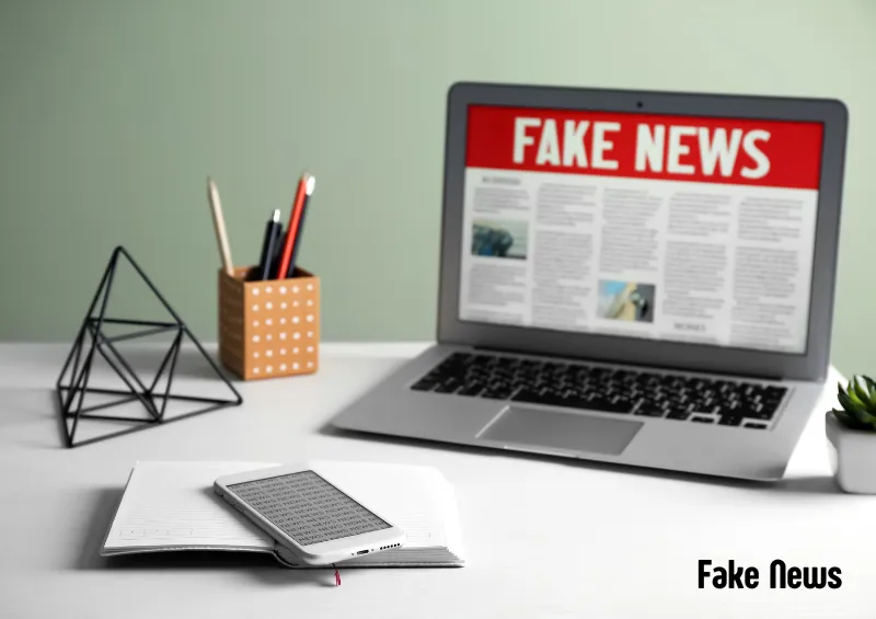 notebook com fake news escrito na tela em cima de uma mesa com um porta lápis e um caderno