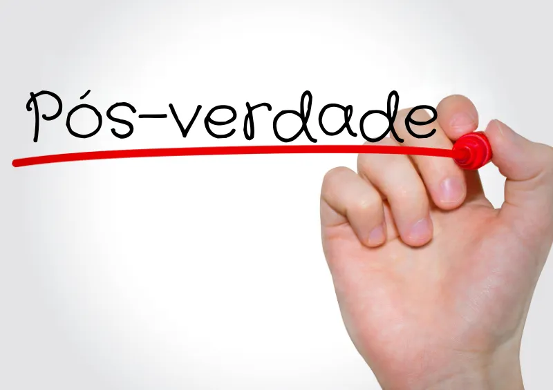 fundo branco com pessoa de mão branca sublinhando a palavra pós-verdade com pilot vermelho